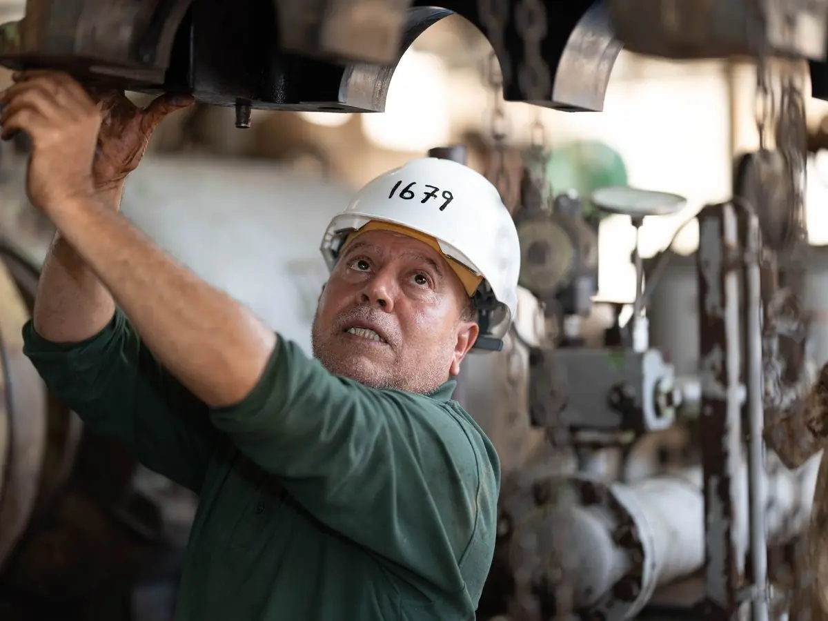 Técnico con casco revisando una máquina en planta